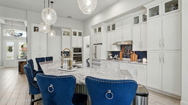 3630 Kite St, Titusville, FL 32796 - kitchen with a center island with sink, backsplash, a kitchen bar, under cabinet range hood, and appliances with stainless steel finishes