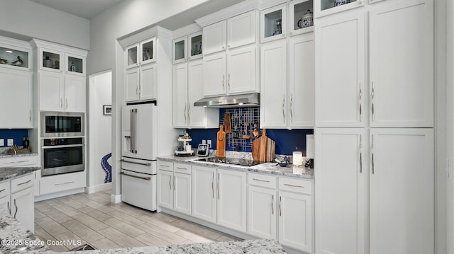 3630 Kite St, Titusville, FL 32796 - kitchen featuring stainless steel appliances, white cabinetry, backsplash, under cabinet range hood, and light stone countertops