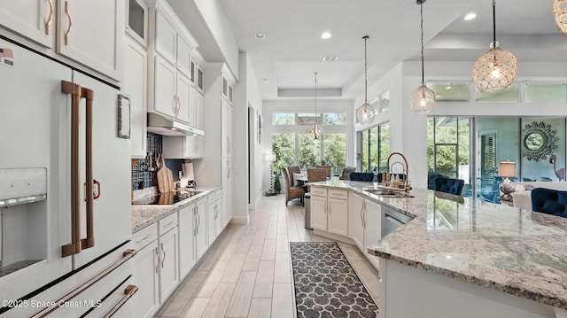 3630 Kite St, Titusville, FL 32796 - kitchen with a sink, white refrigerator with ice dispenser, black electric stovetop, a raised ceiling, and under cabinet range hood