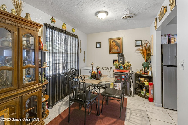 dining area featuring light tile patterned flooring, a textured ceiling, and visible vents