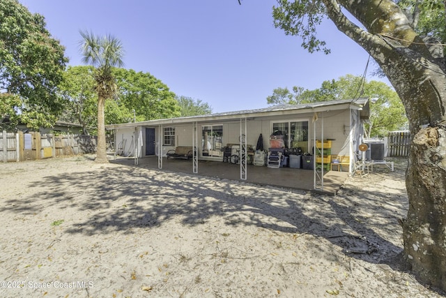 rear view of house featuring fence, concrete block siding, and a patio area