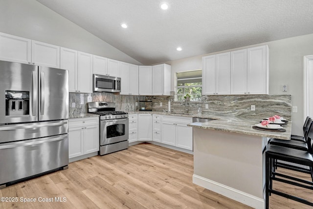 3360 Holly Springs Rd, Melbourne, FL 32934 - kitchen featuring a peninsula, light wood-type flooring, white cabinetry, and stainless steel appliances