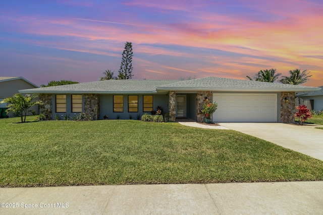 ranch-style home featuring a garage, concrete driveway, a front yard, and stone siding