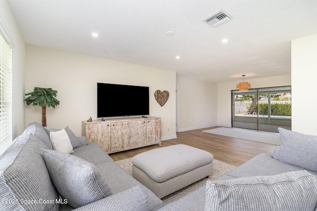living room with wood finished floors, visible vents, and recessed lighting