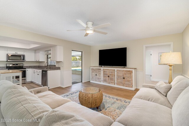 living area featuring light wood finished floors and ceiling fan