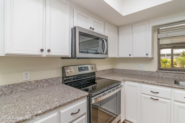 kitchen with light stone countertops, white cabinets, and stainless steel appliances