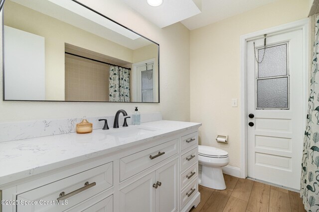 bathroom featuring a shower with shower curtain, baseboards, toilet, wood finished floors, and vanity
