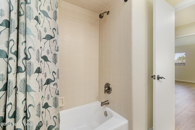full bath featuring wood finished floors, shower / tub combo with curtain, and baseboards