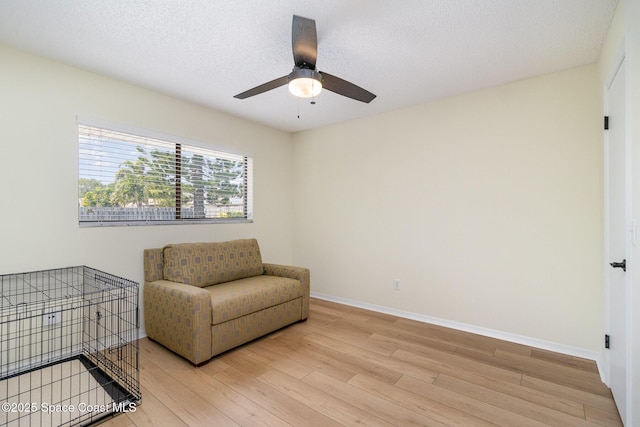 sitting room with ceiling fan, light wood-style flooring, and baseboards
