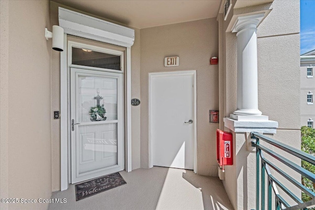 entrance to property with a balcony and stucco siding