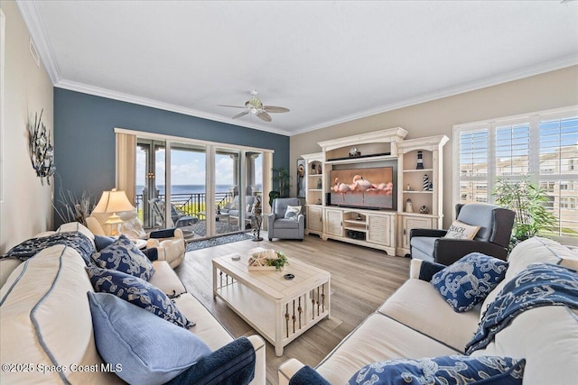 living area with plenty of natural light, a ceiling fan, and ornamental molding