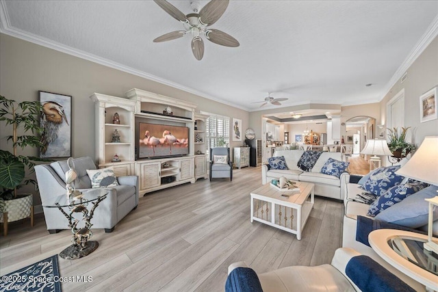 living area featuring light wood finished floors, a textured ceiling, a ceiling fan, and crown molding