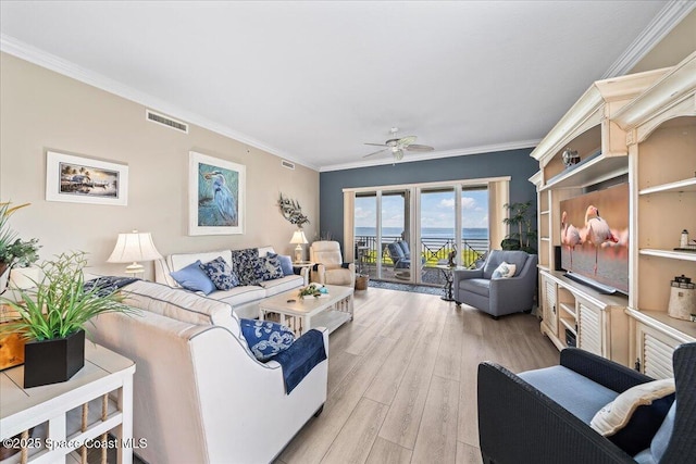 living area with light wood-type flooring, visible vents, crown molding, and ceiling fan