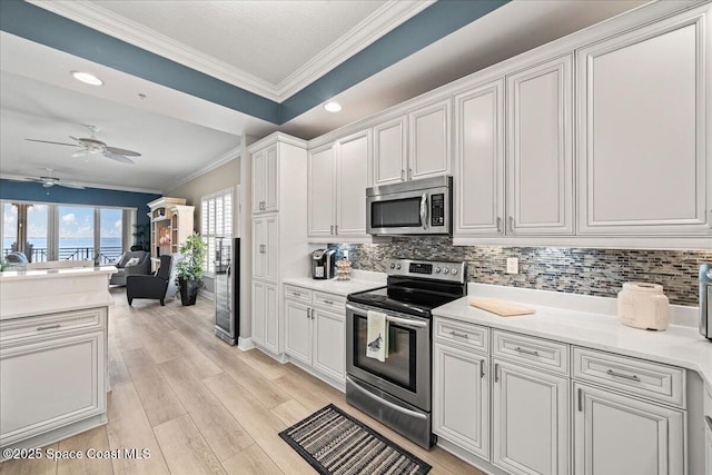 kitchen with tasteful backsplash, crown molding, a ceiling fan, and stainless steel appliances