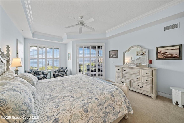 bedroom with a raised ceiling, visible vents, crown molding, and multiple windows