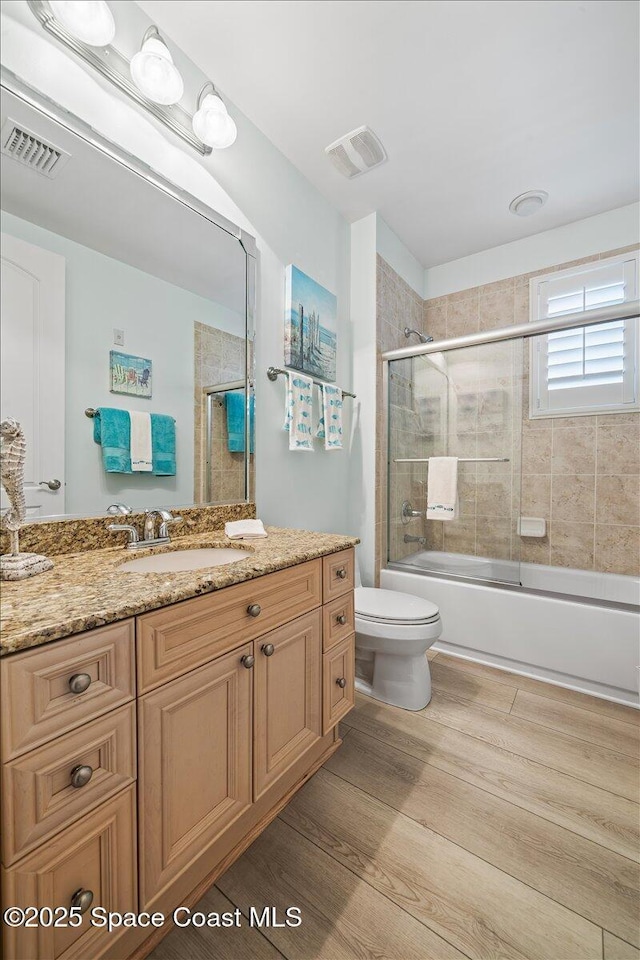 full bathroom featuring vanity, visible vents, bath / shower combo with glass door, and toilet