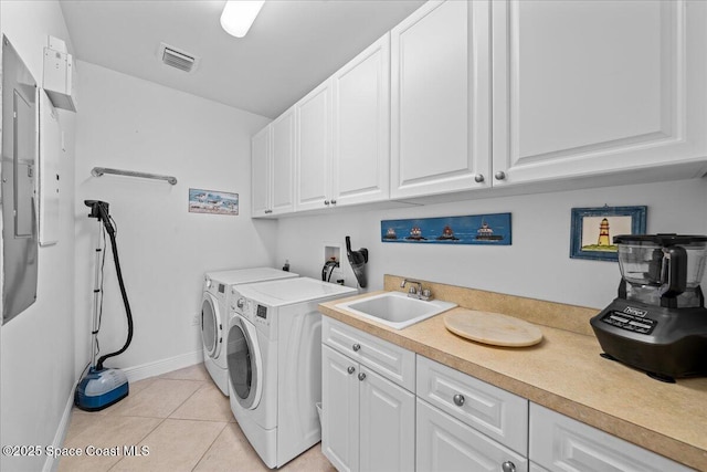 washroom featuring a sink, baseboards, visible vents, independent washer and dryer, and light tile patterned floors
