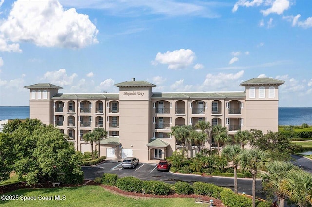view of building exterior featuring uncovered parking and a water view