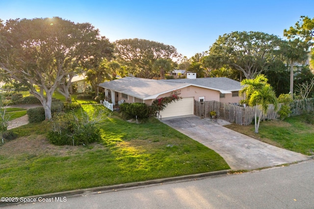 view of front of home with concrete driveway, a garage, fence private yard, a front yard, and stucco siding