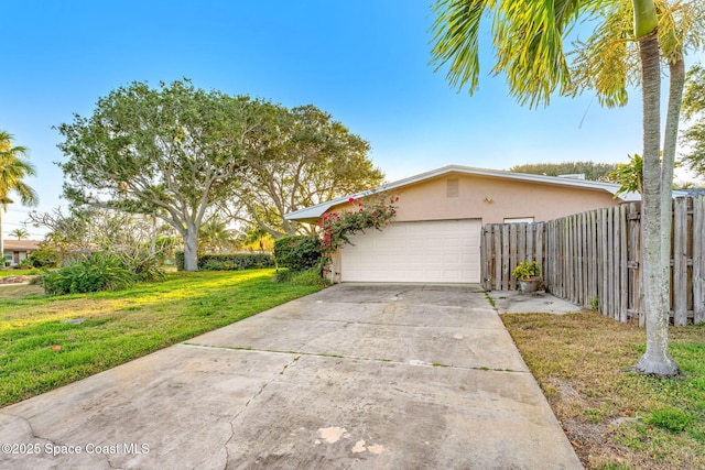 view of front of home featuring a front lawn, driveway, fence, an attached garage, and stucco siding