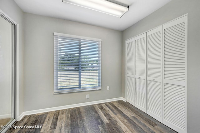 unfurnished bedroom featuring a closet, baseboards, and dark wood finished floors