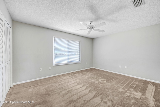 unfurnished bedroom with a textured ceiling, visible vents, carpet flooring, and a closet