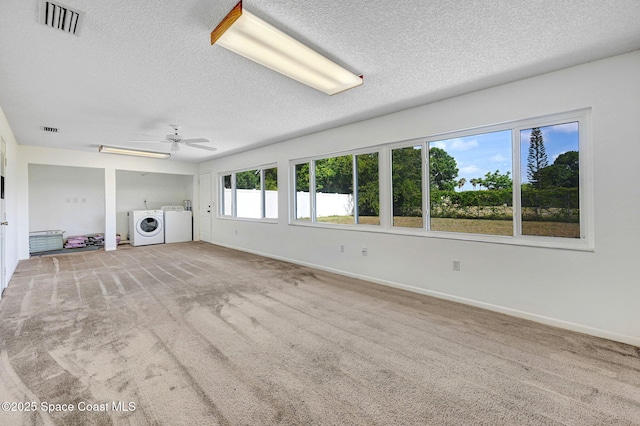 unfurnished living room featuring independent washer and dryer, carpet, baseboards, visible vents, and a textured ceiling