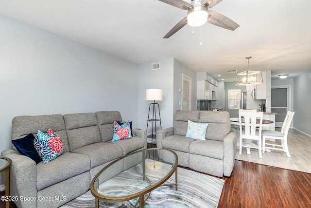 living area with wood finished floors, visible vents, baseboards, and ceiling fan