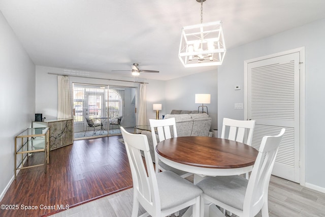 dining space with baseboards, wood finished floors, and ceiling fan with notable chandelier