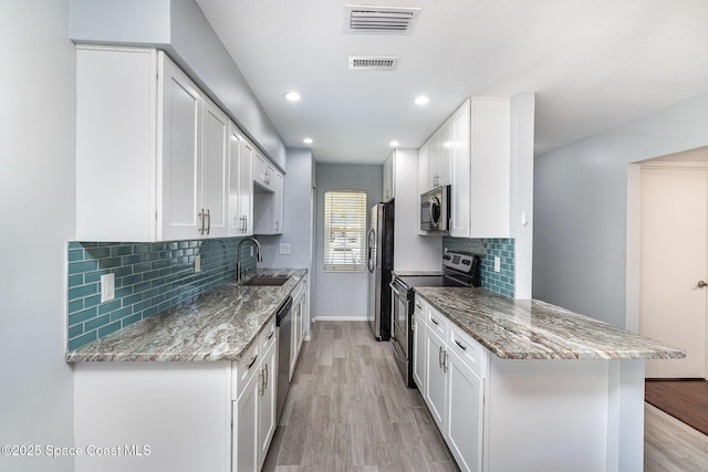 kitchen featuring tasteful backsplash, a sink, light wood-type flooring, appliances with stainless steel finishes, and visible vents
