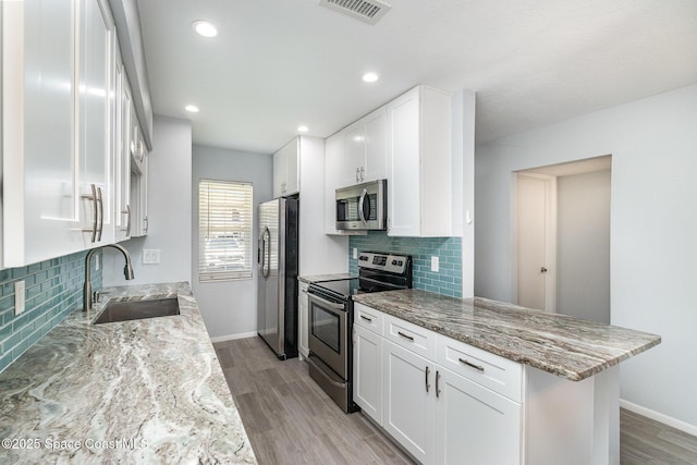 kitchen featuring backsplash, stainless steel appliances, visible vents, and a sink