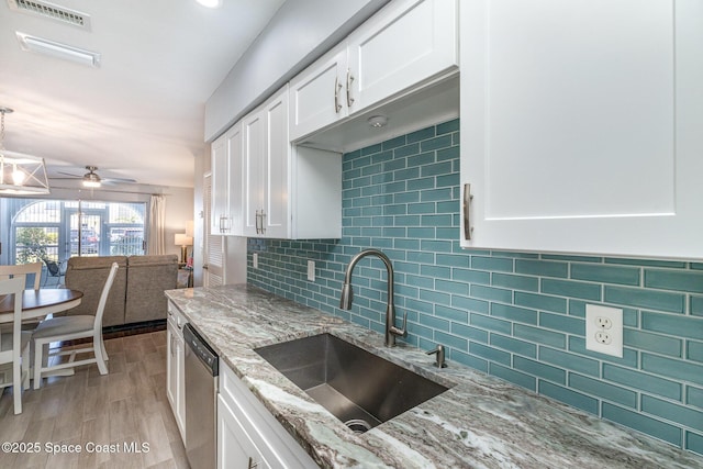 kitchen with white cabinets, visible vents, stainless steel dishwasher, and a sink