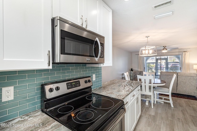 kitchen featuring white cabinets, stainless steel appliances, visible vents, and light stone counters