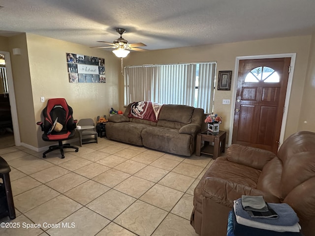 living area featuring ceiling fan, baseboards, light tile patterned flooring, and a textured ceiling