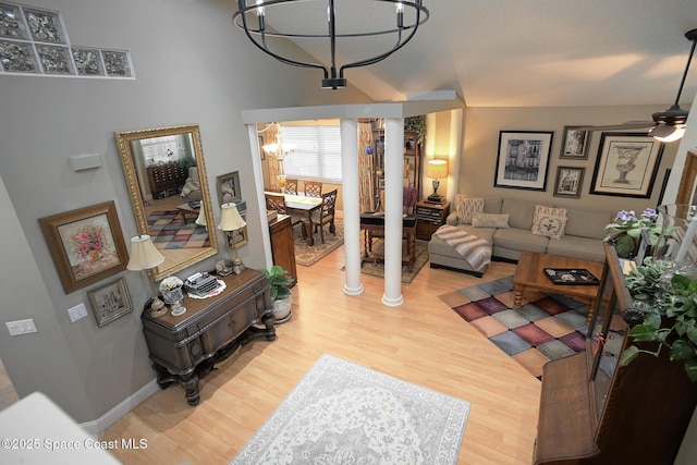 living area featuring ceiling fan with notable chandelier, wood finished floors, and decorative columns