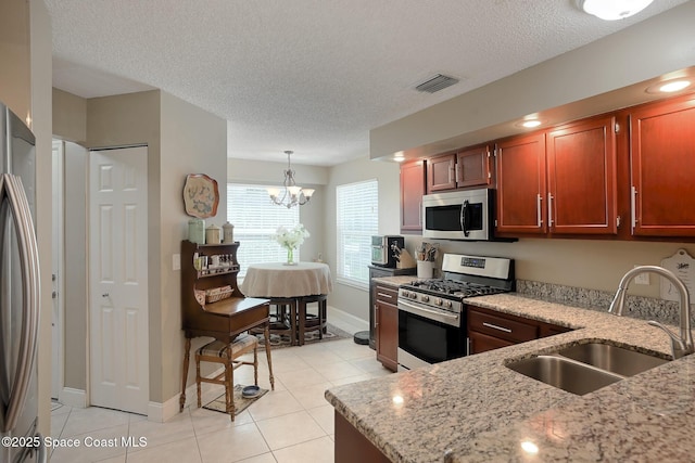 kitchen featuring stainless steel appliances, a sink, light stone counters, and light tile patterned flooring