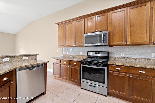 1298 Etruscan Way Unit 119, Indian Harbour Beach, FL 32937 - kitchen with appliances with stainless steel finishes, lofted ceiling, tasteful backsplash, light tile patterned flooring, and brown cabinetry