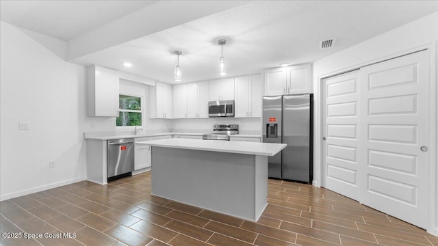 kitchen with white cabinets, stainless steel appliances, visible vents, light countertops, and a kitchen island