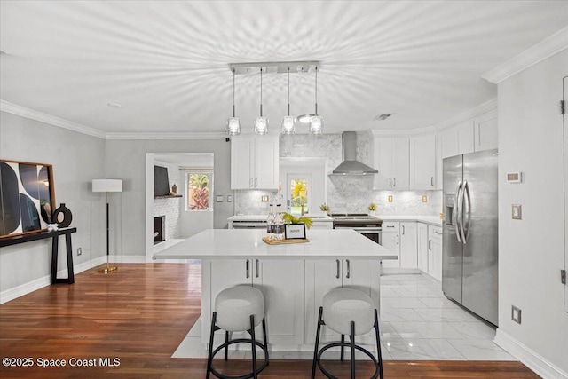 417 E Grant St, Orlando, FL 32806 - kitchen featuring appliances with stainless steel finishes, wall chimney exhaust hood, light countertops, a center island, and white cabinets