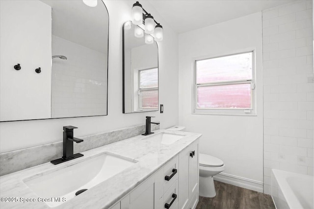 417 E Grant St, Orlando, FL 32806 - bathroom featuring double vanity, wood finished floors, toilet, bathtub / shower combination, and baseboards