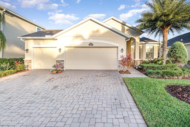 view of front of home with stone siding, stucco siding, and decorative driveway