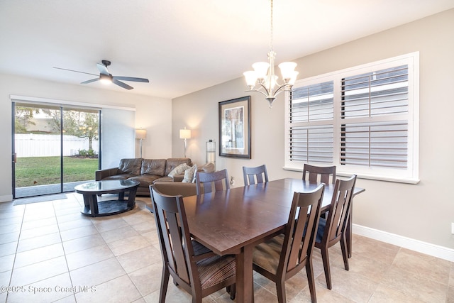 dining space featuring ceiling fan with notable chandelier, baseboards, and light tile patterned floors