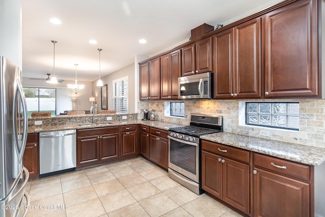 kitchen with backsplash, light stone countertops, stainless steel appliances, and a sink