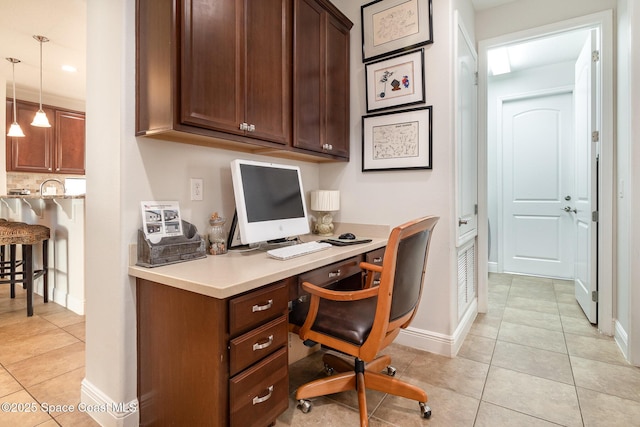 office area with baseboards, built in study area, and light tile patterned flooring