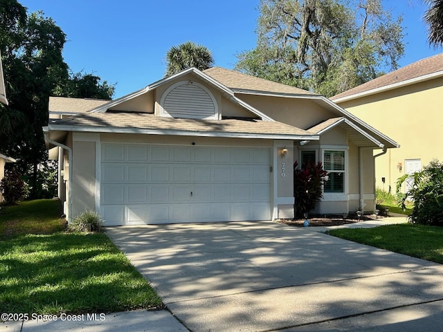 view of front facade featuring a garage, driveway, a front yard, and stucco siding