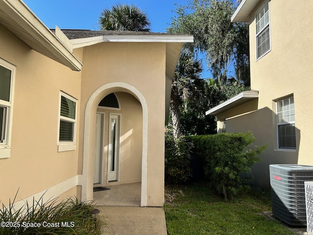 view of exterior entry featuring cooling unit and stucco siding