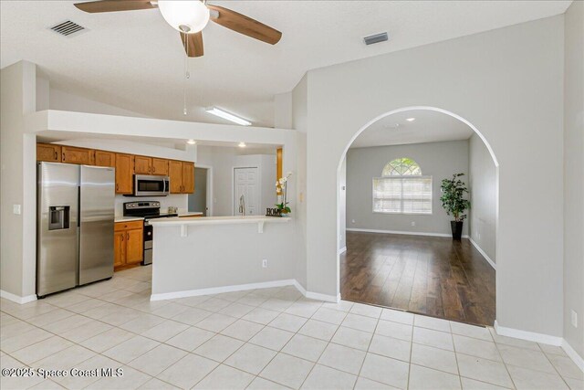 7016 Hammock Trace Dr, Melbourne, FL 32940 - kitchen featuring stainless steel appliances, brown cabinetry, open floor plan, light countertops, and a ceiling fan