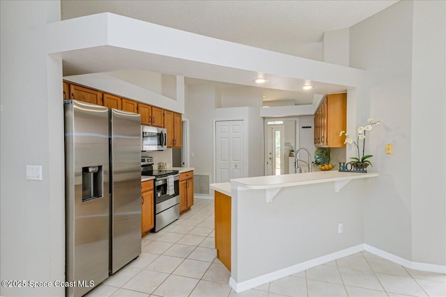 7016 Hammock Trace Dr, Melbourne, FL 32940 - kitchen with stainless steel appliances, brown cabinets, a peninsula, light tile patterned floors, and vaulted ceiling