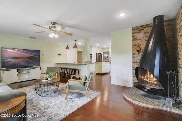 1501 Oranole Rd, Maitland, FL 32751 - living room featuring a wood stove, wainscoting, a ceiling fan, and dark wood-type flooring