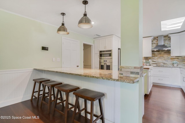 1501 Oranole Rd, Maitland, FL 32751 - kitchen featuring wall chimney range hood, double oven, dark wood finished floors, backsplash, and white cabinetry